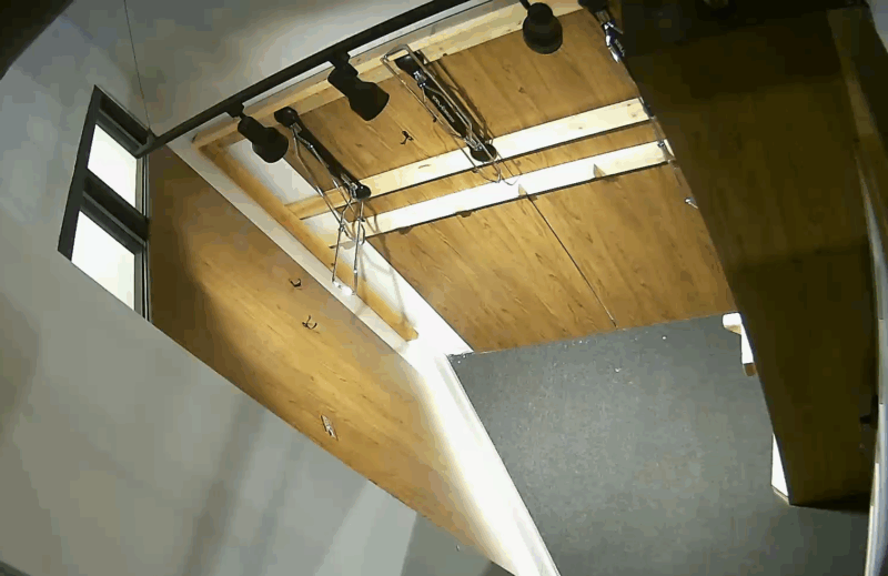 Security camera view of a modern interior with wooden ceiling, black spotlights, carpeted floor, and a Jumbo Closet. Timestamp: 2025-05-15 09:16:03.